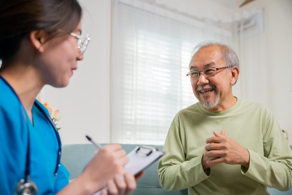 A pharmacist taking notes while talking with an older man