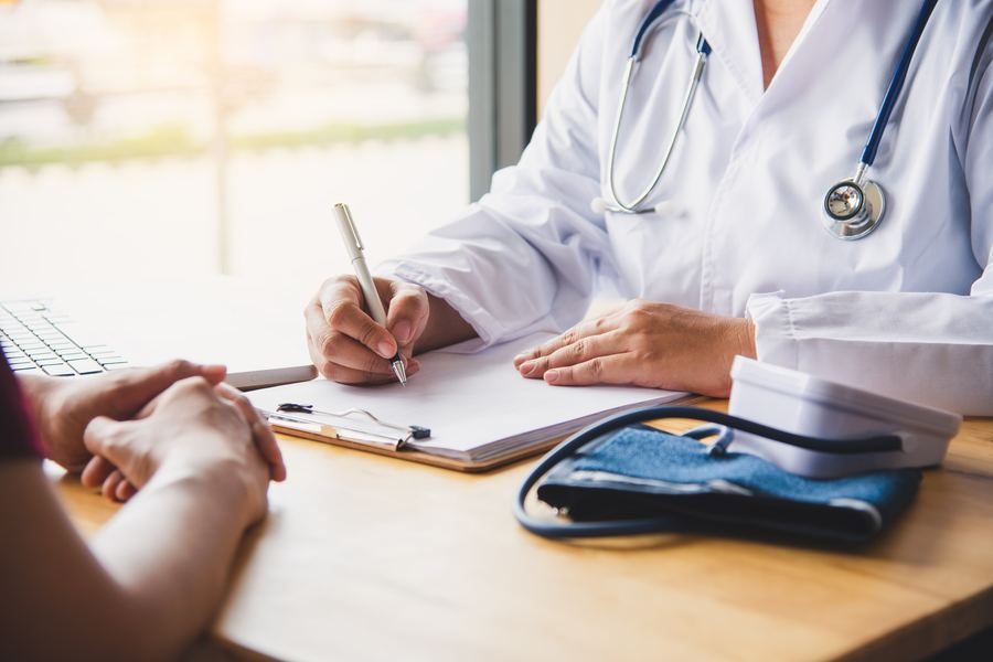 A clinician writing notes beside a blood pressure monitor