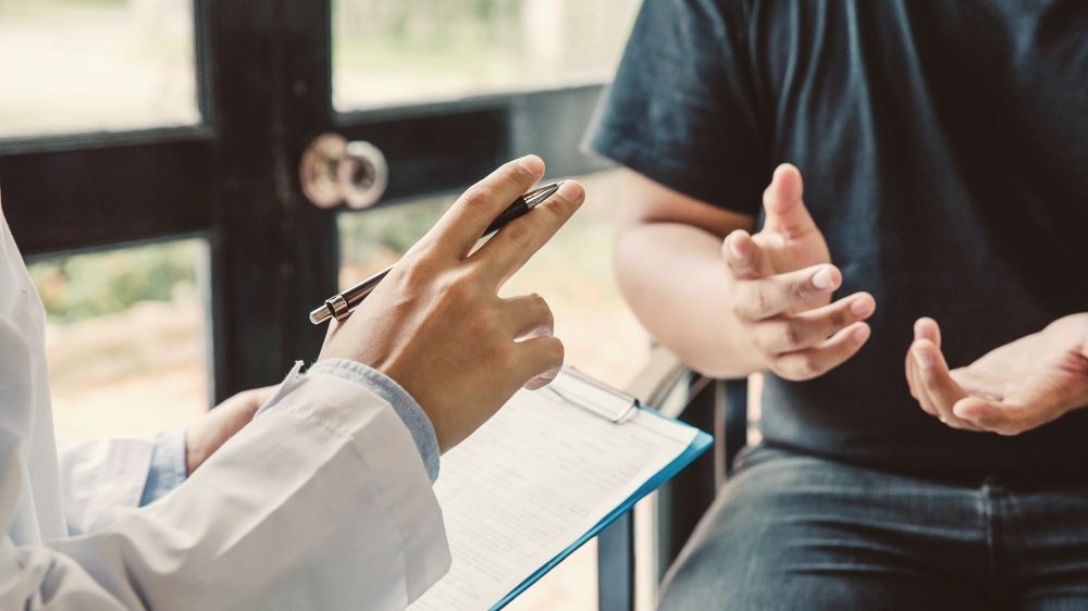 A clinician taking notes during a consultation