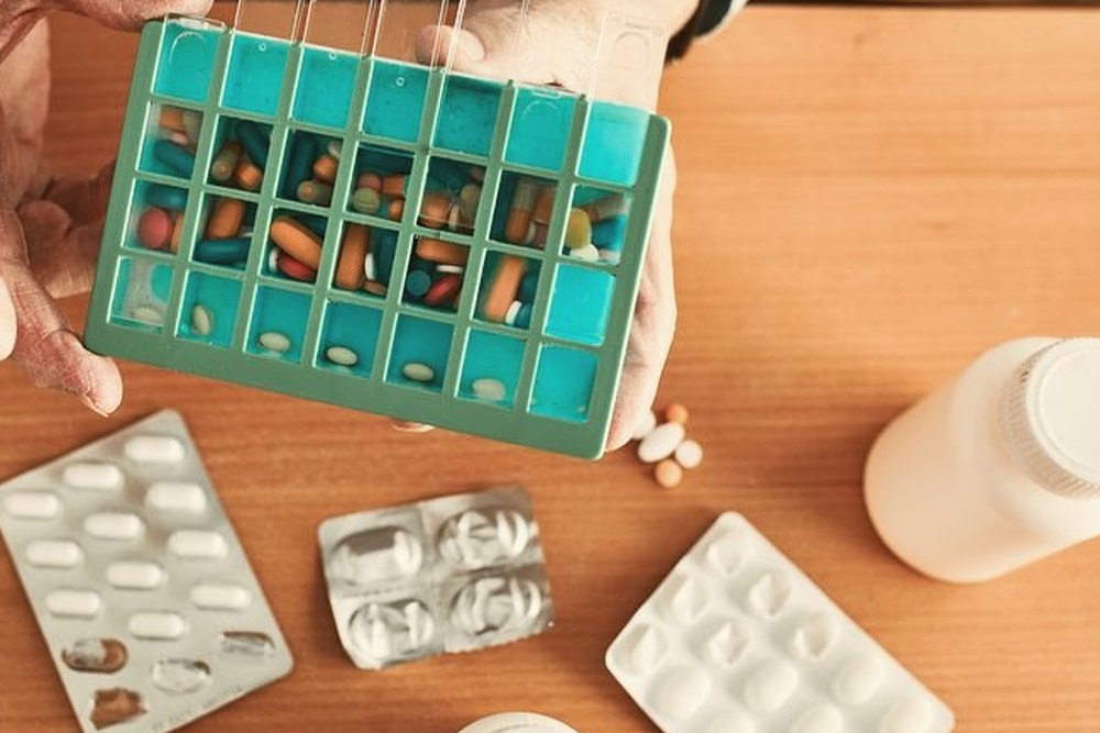 Hands sorting tablets into a weekly dose organiser at home