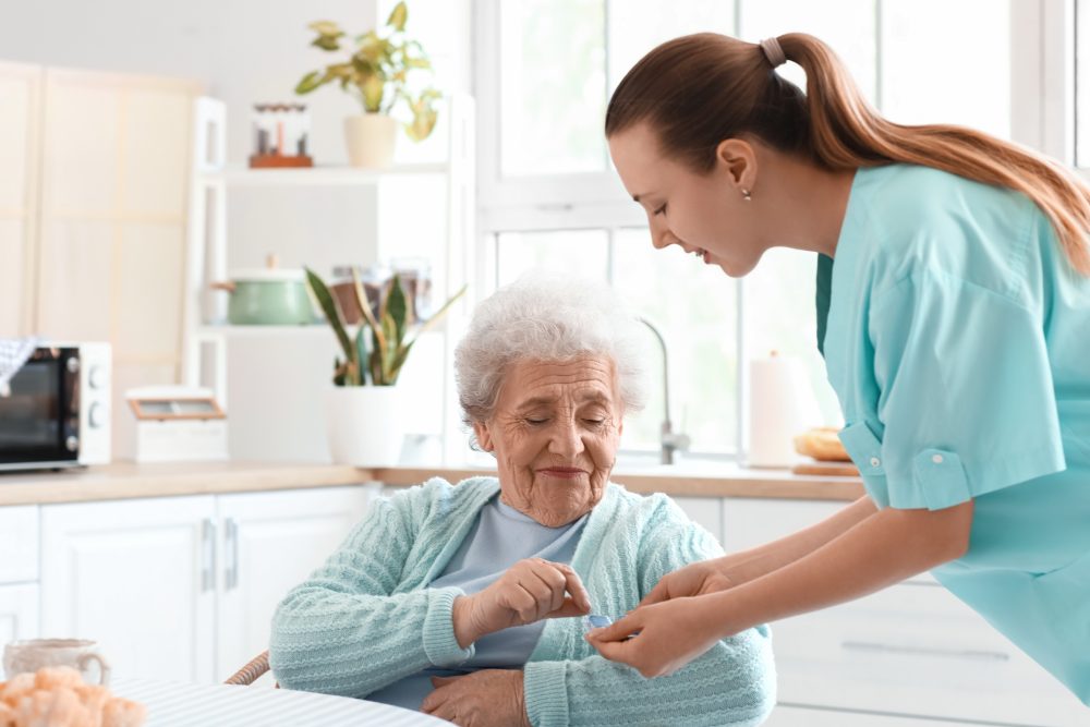 A pharmacist going through medicines with an older woman at her kitchen table