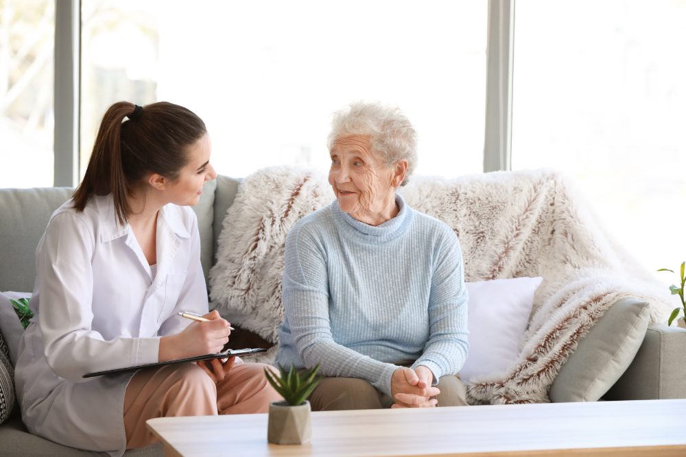 A pharmacist sitting with an older woman at home, going through her medicines