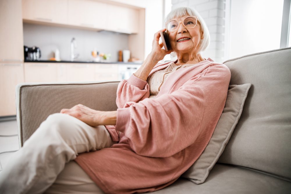 An older woman talking on the phone at home